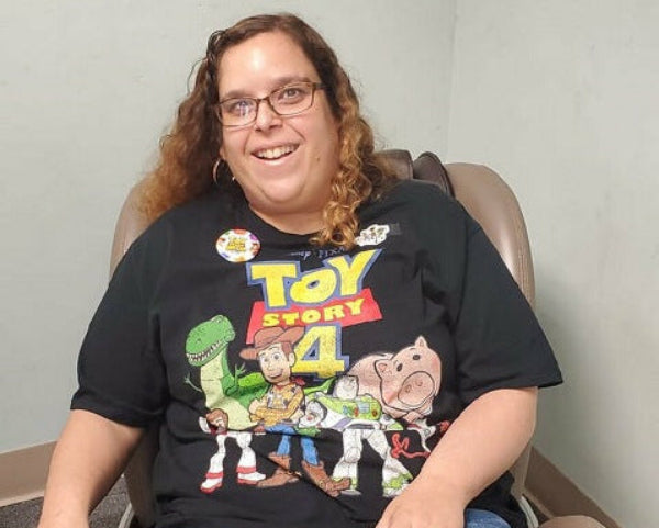Person wearing a 'Toy Story 4' t-shirt sitting in a chair.