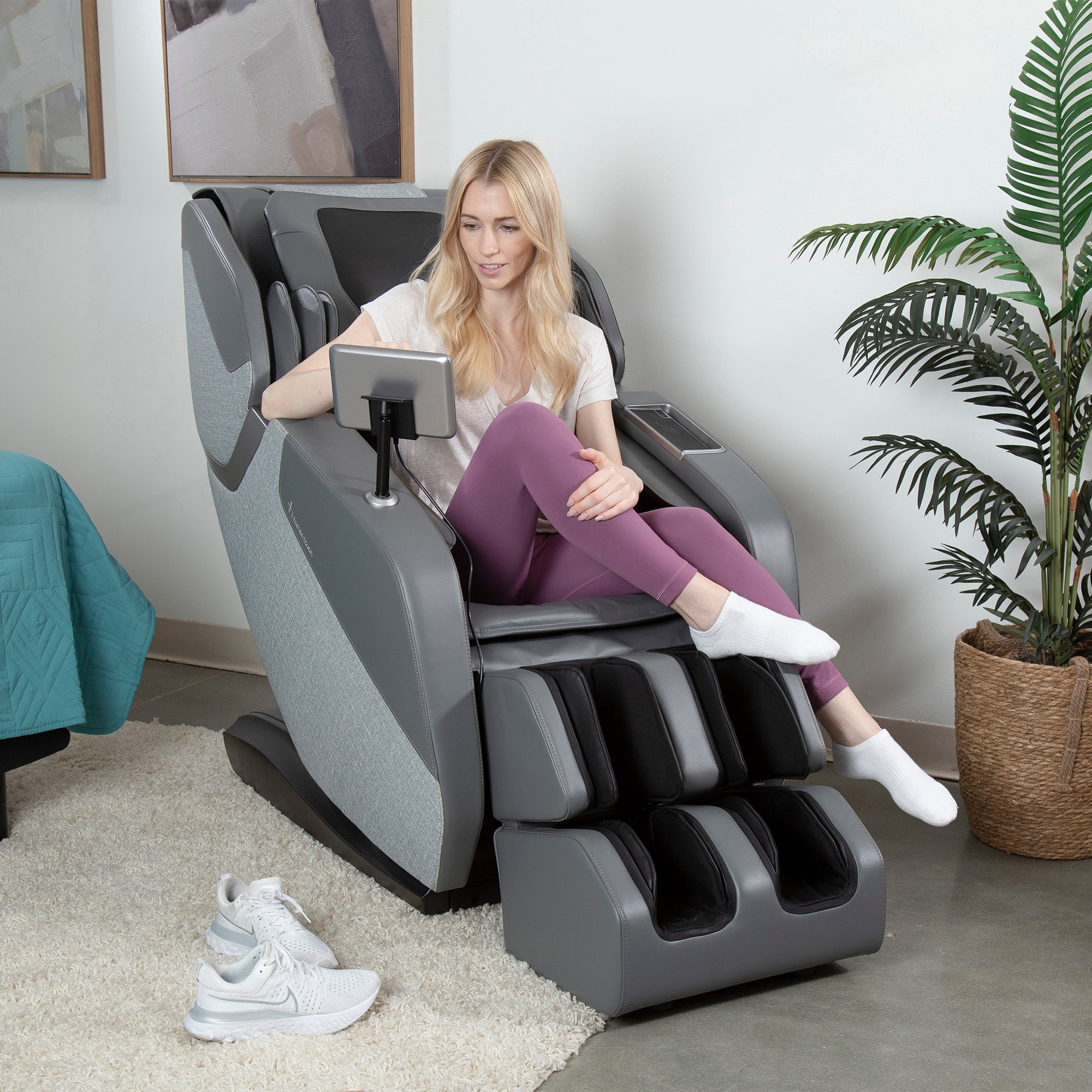 Person relaxing in WholeBody ROVE Massage Chair while using tablet in modern living room setting